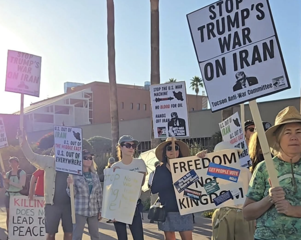Photo of multiple people holding protest signs with phrases like "Stop Trump's War on Iran" and "Killing Does not Lead to Peace."