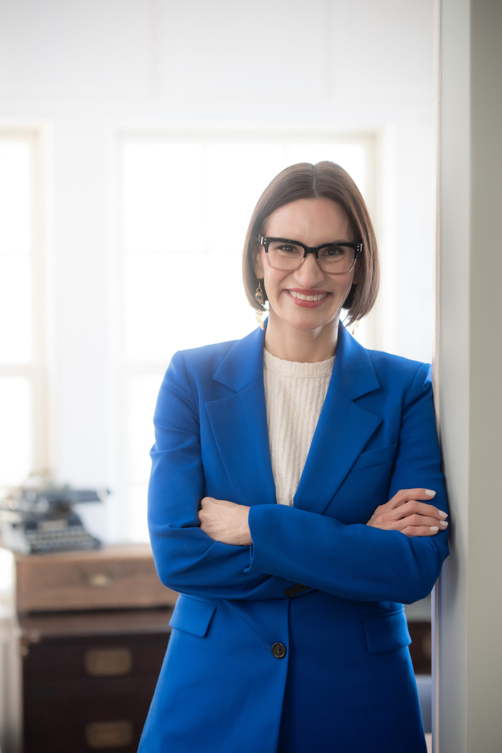 photo of a woman in a bright blue blazer smiling with her arms crossed.
