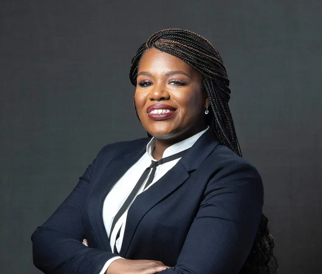 photo of a woman smiling in a black blazer with a white dress shirt.