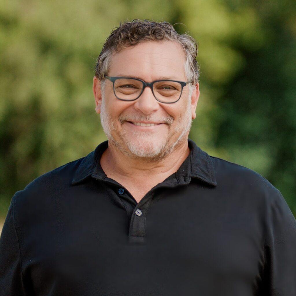 Photo of a man smiling wearing glasses and a dark polo.